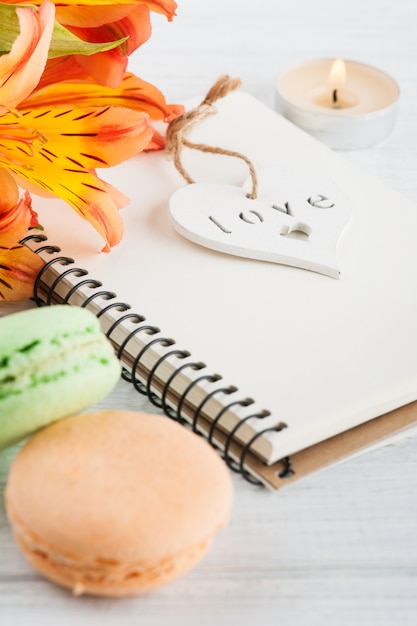 Blank notebook, green orange macaroons, flowers