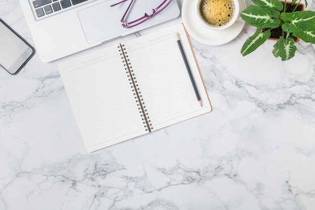 Blank notebook and  Laptop with hot coffee on marble table background, top view and copy space