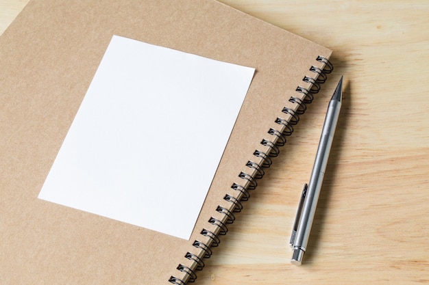 Blank notebook paper with little plants in eco pot on a wooden table picture used for add text or education message green fresh white note with pencil