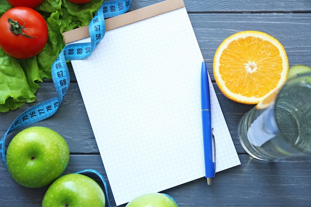 Blank notebook pen and healthy food on wooden table Weight loss concept