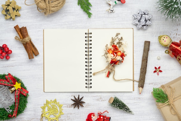 Blank notebook on white wood with Christmas ornaments.