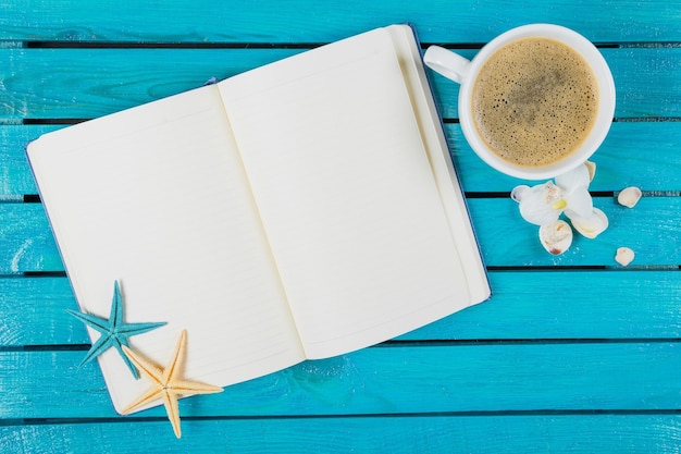 Blank notebook with cup of coffee on blue table background