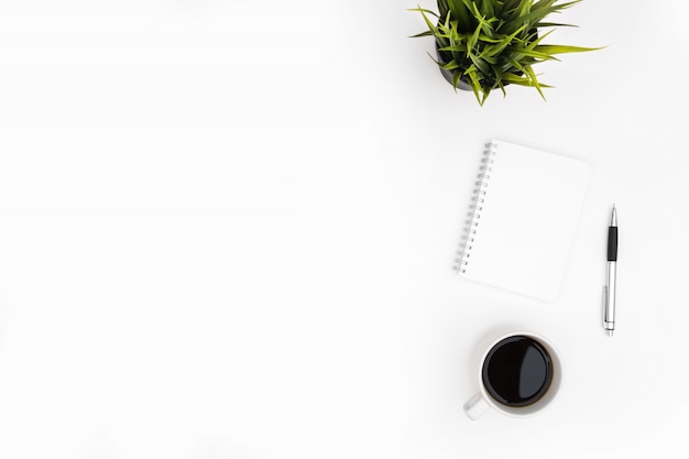 Blank notebook with pen are on top of white office desk table with cup of coffee. Top view with copy space, flat lay.