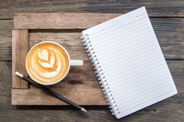 blank notebook with pencil and coffee on wood plate