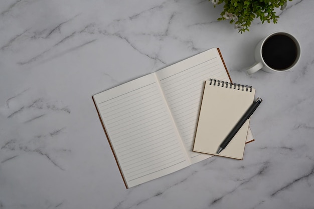 Blank notepad coffee cup and potted plant on marble background Top view with copy space