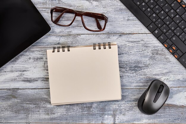 Blank notepad for copy space with glasses and mouse office devices on gray wood