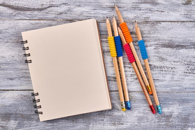 Blank notepad and pencils on gray wooden desk top view flat lay