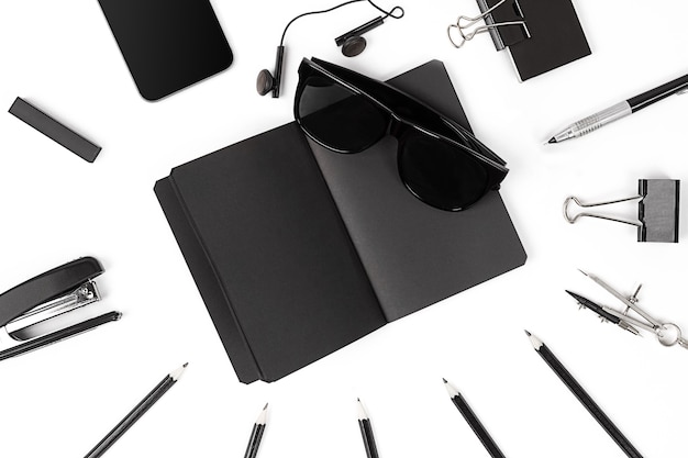 Blank notepad with clips, pens and glasses flat lay.