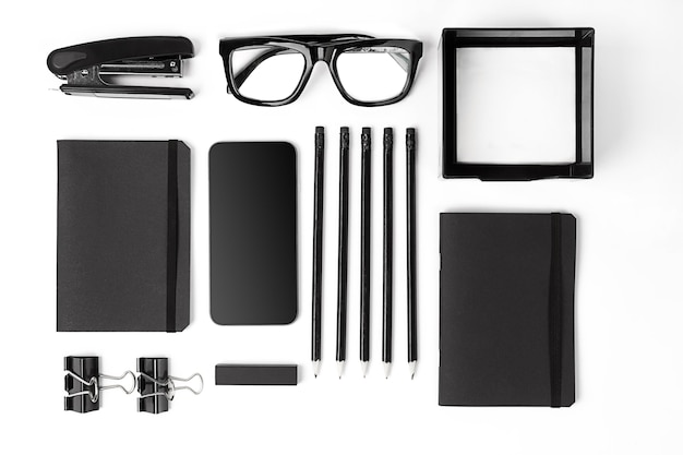 Blank notepad with clips, pens and glasses flat lay.