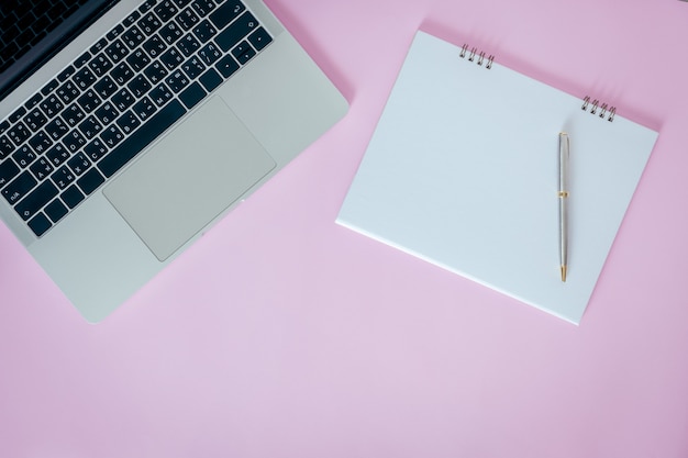 Blank opened notebook with laptop on pink background. flat lay, top view