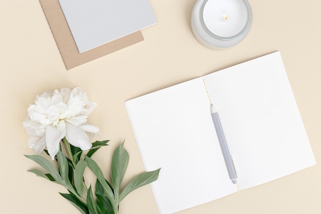 blank pages and white peony flower on table Creative workspace minimal style at home or office