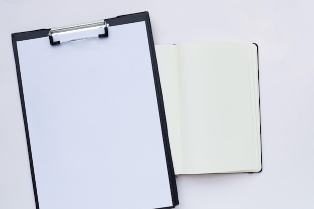 Blank paper in black clipboard with notebook