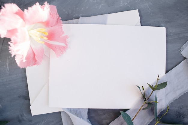 Blank paper copy space. Frame with flowers. Silk ribbon. Gray background. Simple bouquet. Greeting card.