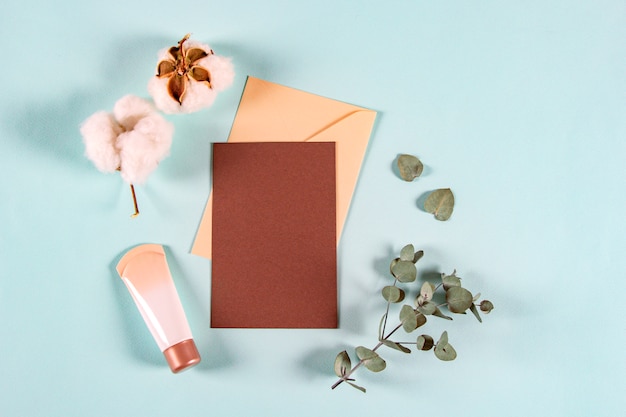 Blank paper envelopes, letters for invitation with eucalyptus leaves, cream jar and cotton flowers