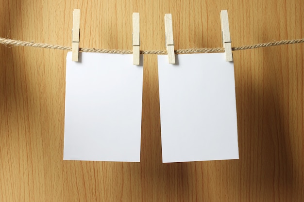 Photo blank paper hangs on the brown rope with wooden paper clips on wood background.