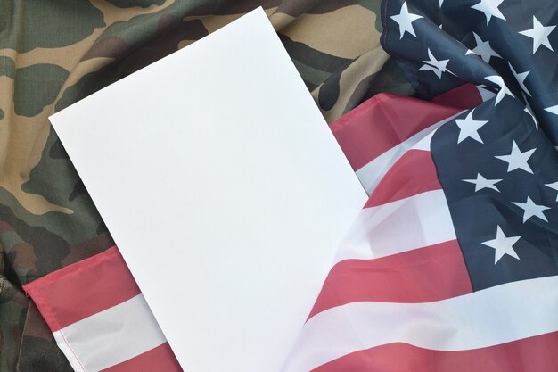 Blank paper laying on United States of America flag and folded military uniform jacket