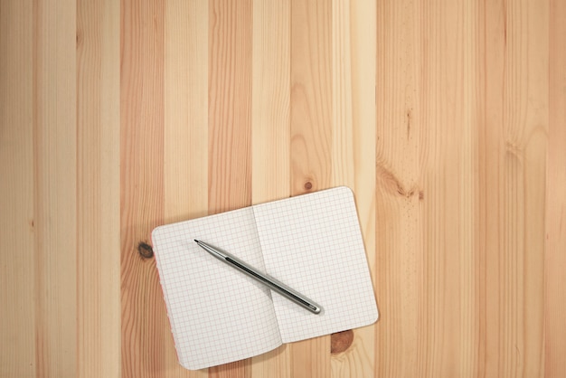 Blank paper notebook on wooden desk with top view for background or backdrop