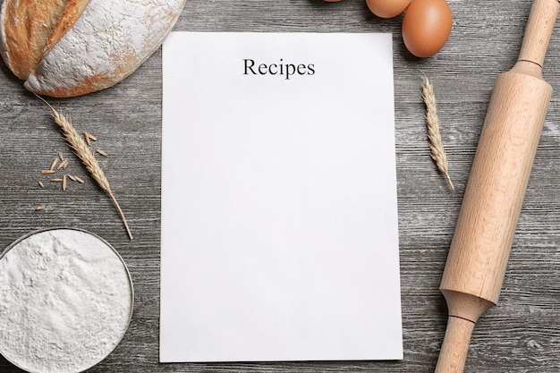 Blank paper sheet and ingredients for cooking bread on wooden background