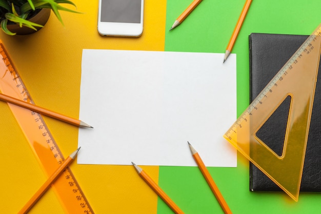 Blank paper with smart phone on desk.top view,flat lay