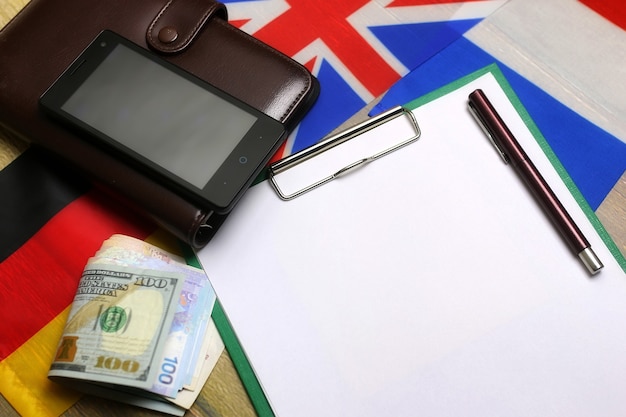 Blank paper on wooden textural desk with mobile phone headphones and flags