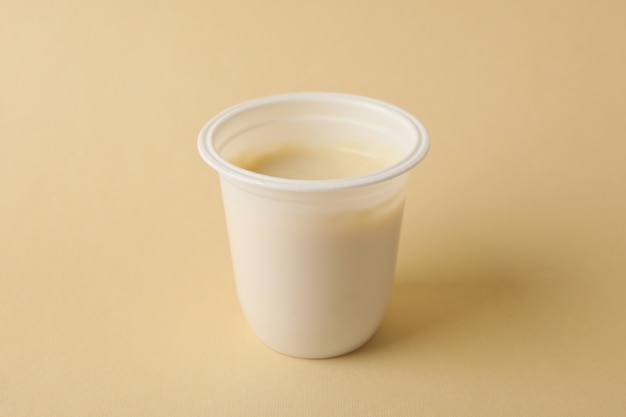 Blank plastic cup of yogurt on beige