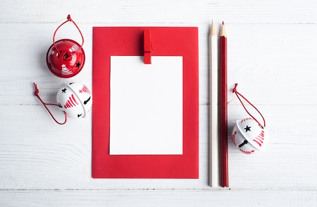 Blank red envelope, empty note and white Christmas toys on wooden rustic, flat lay