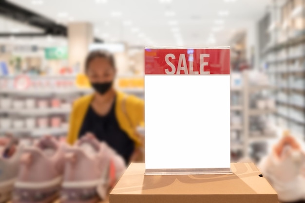 Blank sale sign on a shelf in a supermarket. Blurred background.