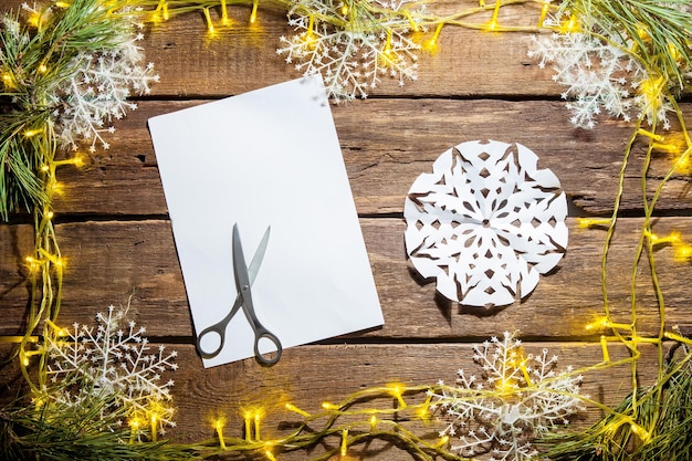 The blank sheet of paper on the wooden table with a scissors