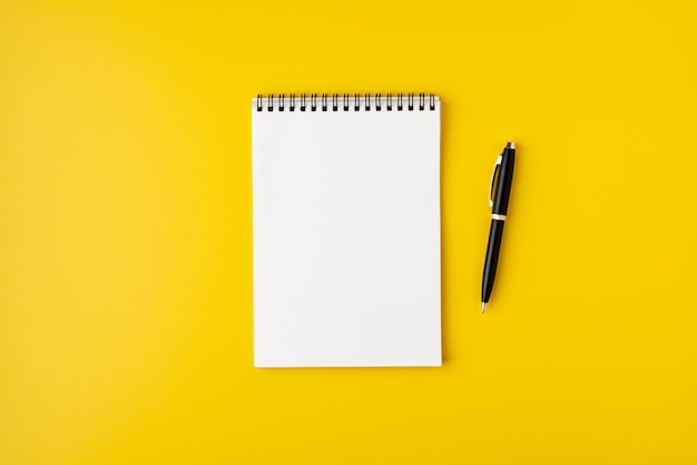 Blank spiral notebook with fountain pen on colorful yellow background top view copyspace