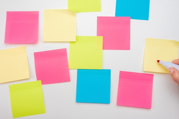 Blank Sticker notes on white background hand with red marker ready to write Mockup sticky Note Paper empty sheets for notes on white bulletin board Colored sticky notes