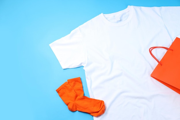 Blank t-shirt, bag and socks on blue background