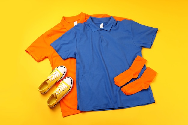 Blank t-shirts, sneakers and socks on yellow background