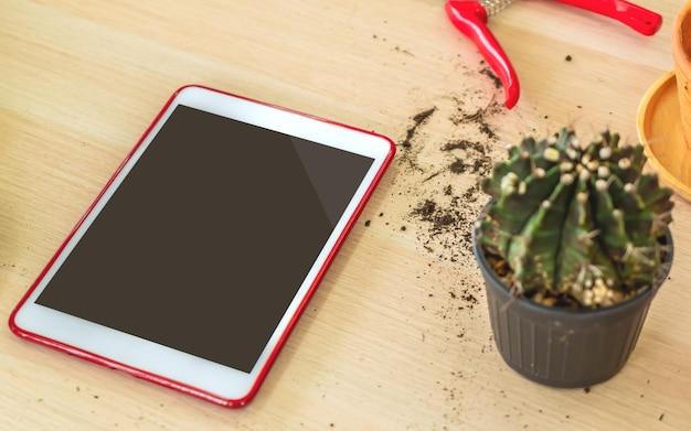 Blank tablet with gardening tools on table for application mock up and template