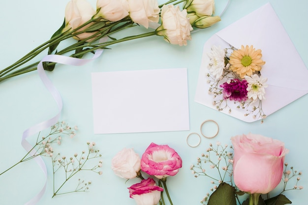 Blank wedding card with two rings and flower decoration on blue background