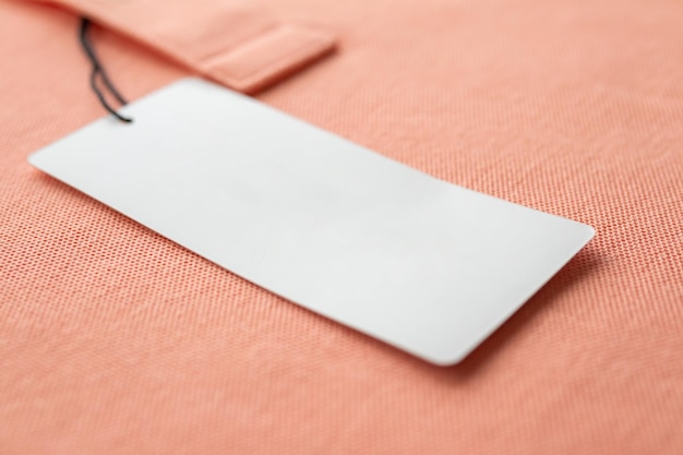 Blank white clothes tag label on pink fabric texture background