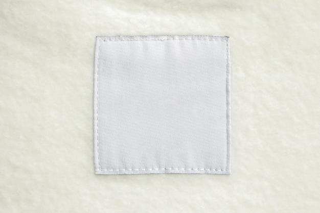 Blank white laundry care clothes label on fabric texture background