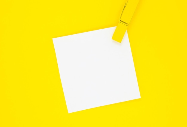 Blank white To Do List Sticker with yellow wooden clothespin. Close up of reminder note paper on the yellow background. Copy space. Minimalism, original and creative photo.