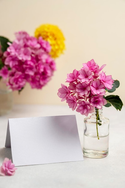 Blank white paper greeting card mock up Pink and yellow flowers in vases with copy space Hydrangea dahlias and eucalyptus