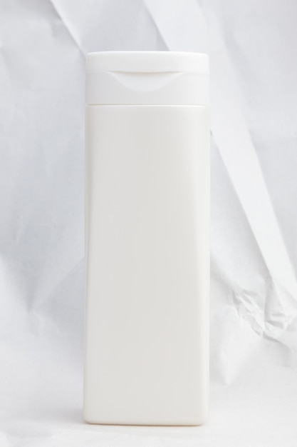 Blank white plastic tube for shampoo or cream on a light background