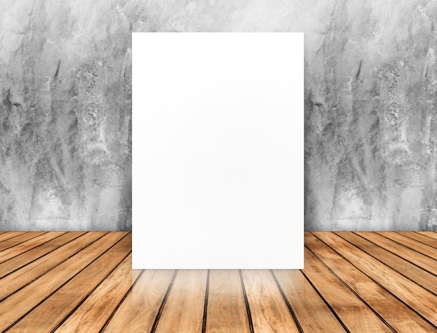 Blank white poster leaning at concrete wall on wood plank floor,