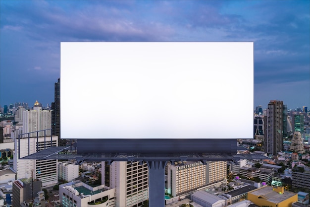 Blank white road billboard with Bangkok cityscape background at night time Street advertising poster mock up 3D rendering Front view The concept of marketing communication to promote idea