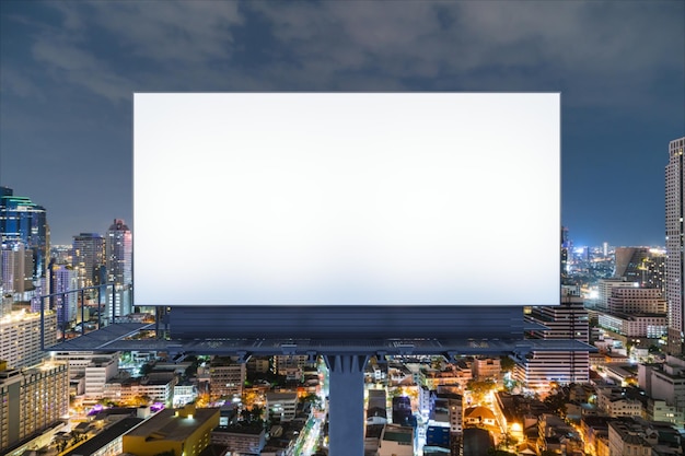 Blank white road billboard with Bangkok cityscape background at night time Street advertising poster mock up 3D rendering Front view The concept of marketing communication to promote idea