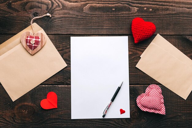 Photo blank white sheet in an envelope on a wooden table next to it is a ballpoint pen declaration of love on st valentine's day