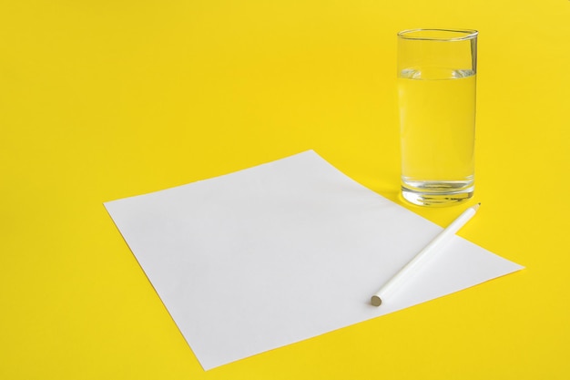 Blank white sheet of paper with a glass of water and a pencil