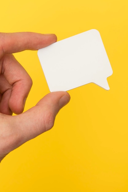 Blank white speech bubble held in a hand on a bright yellow background