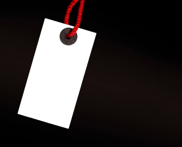 blank white tag on red thread on black background