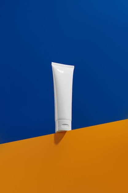 Blank white tube bottle with skin care product on blue and orange creative background