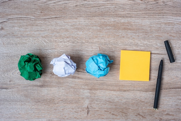 Blank yellow note with pen and crumpled papers