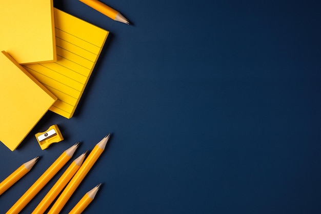 Blank yellow sticky note and pencil on navy blue table background