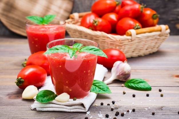 Blended fresh tomato juice with basil leaves in glasses  on a wooden table